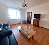 Wohnzimmer mit Sofa, Tisch und Fernseher, Boden mit Holzdekor in einer 3-Zimmer-Wohnung.