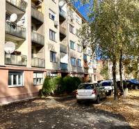 Wohnhaus in der Mederčská-Straße in Komárno mit geparkten Autos und Bäumen.