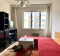 Wohnzimmer in einer 3-Zimmer-Wohnung mit rotem Sofa, Teppich, älterem Fernseher, heller Raum.