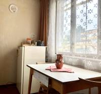 Esszimmer in einer 3-Zimmer-Wohnung mit Tisch, Stühlen und Vorhängen mit Blumenmuster.