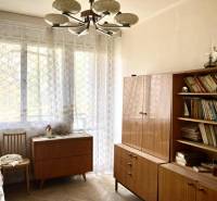 Ein Zimmer in einer 3-Zimmer-Wohnung mit Büchern, Holzmöbeln und einem Boden mit Holzdekor.