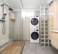 Badezimmer in einer 4-Zimmer-Wohnung mit Waschmaschine, Dusche und Boden mit Holzdekor.
