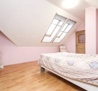 Helles Schlafzimmer mit doppelschrägigen Dachfenstern und Boden in Holzoptik in einer 4-Zimmer-Wohnung.