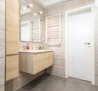 Badezimmer mit Waschbecken, Spiegel und hellen Fliesen in einer 4-Zimmer-Wohnung.