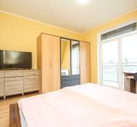 Schlafzimmer in einer 4-Zimmer-Wohnung mit Schränken, Kommode, TV und Boden mit Holzdekor.