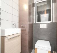 Badezimmer in einer 4-Zimmer-Wohnung mit hellen Fliesen, Waschbecken und Toilette.