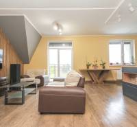 Wohnzimmer einer 4-Zimmer-Wohnung mit Holzboden, bequeme Sitzgelegenheiten und Licht.