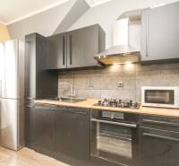 Küche in einer 4-Zimmer-Wohnung mit schwarzen Schränken und einem Boden in Holzoptik.