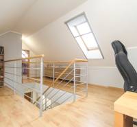 Dachgeschoss eines 4-Zimmer-Wohnung mit einem Arbeitsstuhl und einem Bücherregal, Boden mit Holzdekor.