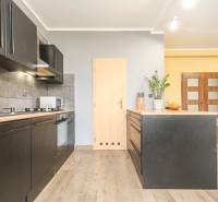 Küche in einer 4-Zimmer-Wohnung mit schwarzen Schränken und einem Boden in Holzoptik.