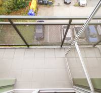 Balkon in einer 4-Zimmer-Wohnung mit Blick auf den Parkplatz und Grünflächen.