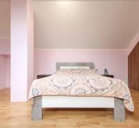 Helles Schlafzimmer, Boden mit Holzdekor, geneigte Decke, bequemes Bett, Stauraum.