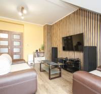 Wohnzimmer in einer 4-Zimmer-Wohnung mit Fernseher, Sofa und Holzboden.