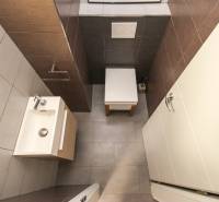 Badezimmer in einer 4-Zimmer-Wohnung mit Waschbecken, farbigen Fliesen und kompaktem Design.