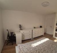 Schlafzimmer in einer 3-Zimmer-Wohnung mit Holzboden, Einbauschrank und Schreibtisch.