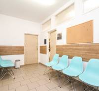 Wartezimmer mit blauen Stühlen, Korkpinnwand und Holzboden in einem Büro.