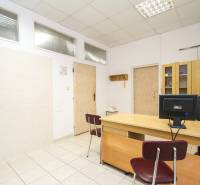 Büros mit einem Tisch, einem Stuhl, einem Computer und einem Schrank auf einem hellen Keramikboden.