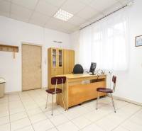 Ein Büro mit Holzmöbeln, einem Computer und Dekorationen an den Wänden, Fliesen auf dem Boden.