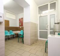 Ein Wartezimmer im Büro mit türkisfarbenen Stühlen und einem Wasserbehälter.