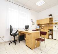 Büro mit Computer, Tisch und Stuhl, heller Innenraum, Regale und Waschbecken.