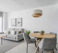 Helles Wohnzimmer der Ferienwohnung mit grauem Sessel und Holztisch.