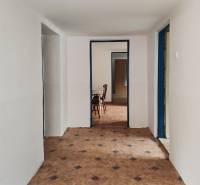 Ein Flur in einem Einfamilienhaus mit Fliesenboden und Möbeln im Hintergrund.