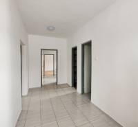 Der Flur des Einfamilienhauses mit Fliesen und weißen Wänden, der zu einer Tür führt.