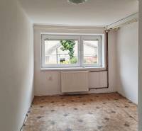 Kleine Zimmer mit hellen Wänden, großem Fenster und gemustertem Boden in einem Einfamilienhaus.