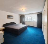 Ein Schlafzimmer in einem Einfamilienhaus mit einem großen Bett, einem blauen Teppich und einem Einbauschrank.