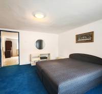 Schlafzimmer in einem Einfamilienhaus mit großem Bett, blauem Teppich und Bild an der Wand.