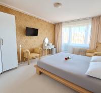 Schlafzimmer in einer 3-Zimmer-Wohnung mit elegantem Möbeln, goldener Tapete und weißem Teppich.