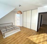 Ein Schlafzimmer in einem Einfamilienhaus mit einem Bett, einem Einbauschrank und einem Boden mit Holzdekor.