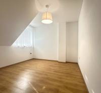 Ein Raum in einem Einfamilienhaus mit einem Holzboden, einer einfachen Lampe und einem großen Fenster.