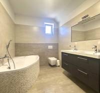 Badezimmer mit Badewanne, Doppelwaschbecken und Spiegel in einem Einfamilienhaus.