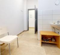 Geschäftsräume mit Waschbecken, weißer Wand und Boden in Holzoptik.