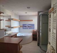 Badezimmer in einer 2-Zimmer-Wohnung, mit Badewanne, Dusche und Regalen.