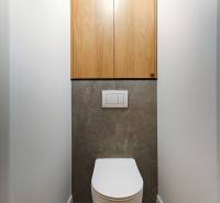 Toilette in einer 2-Zimmer-Wohnung mit dunklem Steinboden und Holzschränken.