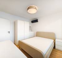 Schlafzimmer in einer 2-Zimmer-Wohnung mit Bett, Schrank, Kommode und Boden in Holzoptik.