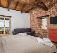 Schlafzimmer in einer Villa mit Ziegelwänden, Fernseher, Sofa und großem Bett.