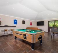 Innenraum einer Villa mit Billardtisch, Ledersofa und Holzboden.