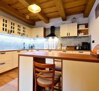 Eine Küche in einer Hütte mit Holzdecke, einem Boden mit Holzdekor und blauen Fliesen.