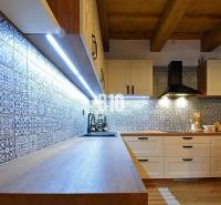 Küche in einer Hütte mit Fliesen und Holzboden, beleuchtet mit LED-Lichtern.