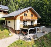 Eine Hütte in Terchová, umgeben von Wald, mit einem Parkplatz und einer Terrasse.