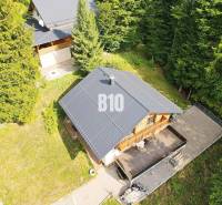 Eine Hütte in Terchová, umgeben von Wald, mit einer Holzterrasse und einem angrenzenden Garten.