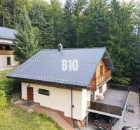 Eine Hütte in Terchová, umgeben von Wäldern, mit großer Terrasse und Parkplatz.