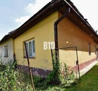 Ein Einfamilienhaus in Partizánska Ľupča, gelbe Fassade, alter Zaun mit Maschendraht.