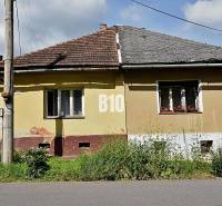 Ein gelbes Einfamilienhaus in Partizánska Ľupča mit einem schrägen Dach und einem angrenzenden Garten.