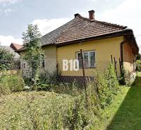 Ein Einfamilienhaus in Partizánska Ľupča mit einem eingezäunten Garten und einer verblassten Fassade.