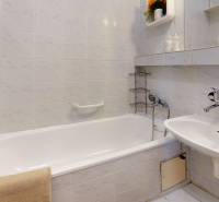 Badezimmer in einer 3-Zimmer-Wohnung mit Badewanne, Waschbecken und weißen Fliesen.