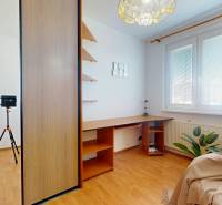 Ein Zimmer mit einem Eckschreibtisch, einem Einbauschrank und einem Boden mit Holzdekor in einer 3-Zimmer-Wohnung.